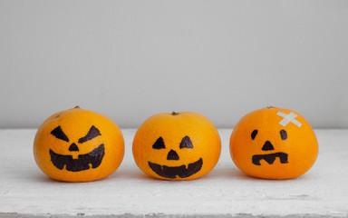 Fresh Orange with Head Pumpkins  haunted spooky face  easy DIY decoration for Halloween festival, on white wood with copy space