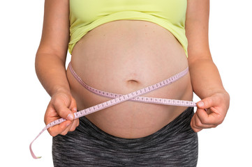 Pregnant woman is measuring belly with tape meter