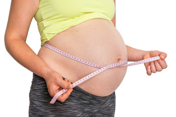 Pregnant woman is measuring belly with tape meter