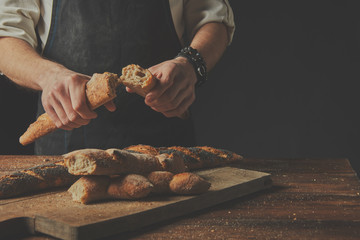 The baker keeps the baguette halves in his hands. - obrazy, fototapety, plakaty