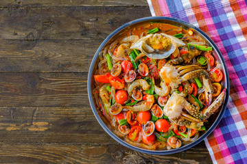 Som Tam Seafood (Spicy Papaya Salad) with salted crab, on wooden table ( Thai food)