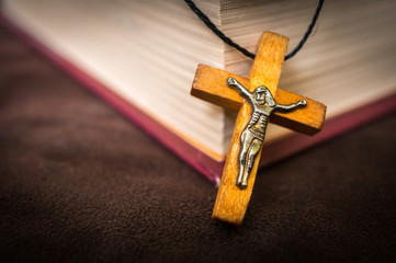 Christian wooden cross necklace on holy Bible