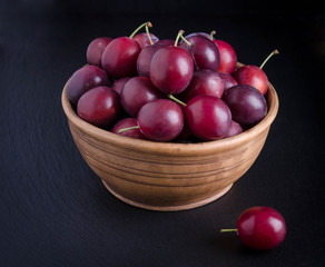 ripe plums in the bowl on black background