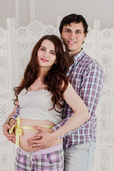 Young couple expecting baby standing together indoors