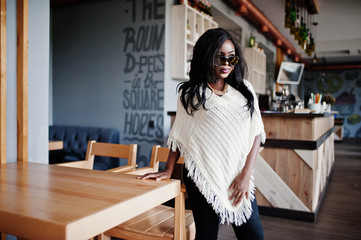 Stylish african american girl in sunglasses posed at modern cafe.