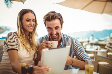 Happy couple checking menu at the tablet
