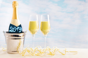 Champagner Flasche und Gläser vor einem blauen Hintergrund mit der Zahl 2019 auf der Flasche