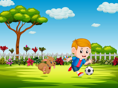 the boy playing soccer in the yard with his dog 
