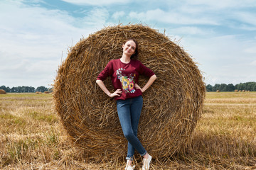 Naklejka na ściany i meble young girl having fun in the field, mowed hay wrapped in a haystack