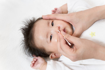 Obraz na płótnie Canvas 新生児の鼻掃除方法を説明するマニュアル用写真、鼻を綿棒で清潔にするクローズアップ