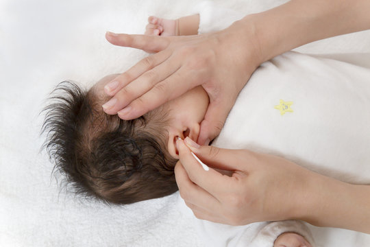 新生児の耳掃除方法を説明するマニュアル用写真、耳を綿棒で清潔にするクローズアップ