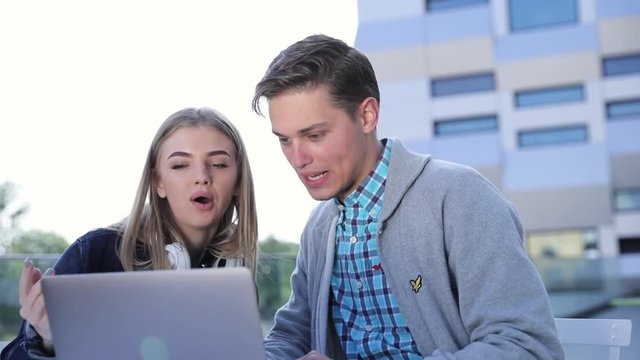 Young Man And Woman Working On Computer Outdoors