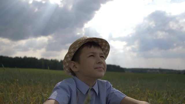 dreamer boy in the hat looks at the beautiful sky in the field