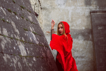 Obraz na płótnie Canvas Concept of Halloween. Beautiful and simple costume of little red hood. Mysterious hooded lady figure . Girl in red raincoat. Cosplay Fairy Tale Little Red Riding Hood 