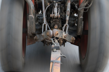Fototapeta premium An old tractor ride on asphalt road and pulls a load with rod.