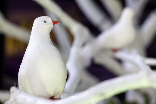 Artificial white bird make romantic decoration of the garden. Beautiful cute bird sitting on a branch.