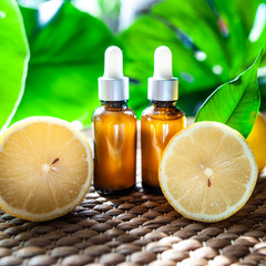 Bottles with lemon oil, fresh  fruit whole and half on a natural tropical background.