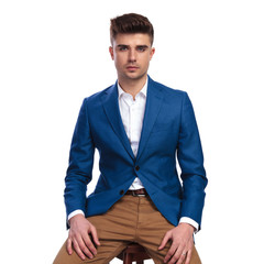 serious smart casual man sitting on a stool