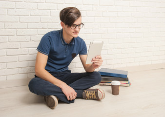 Young man sits with textbooks on the floor