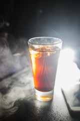 a glass of whiskey, or rum, or alcohol stands on a table on a dark background in the bar