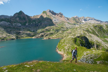 Fototapeta na wymiar man hiker climbing a slope, Lake Estaens in the background