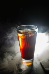 a glass of whiskey, or rum, or alcohol stands on a table on a dark background in the bar