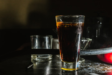 a glass of whiskey, or rum, or alcohol stands on a table on a dark background in the bar
