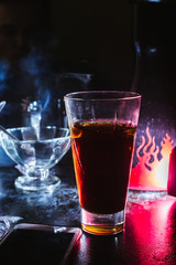 a glass of whiskey, or rum, or alcohol stands on a table on a dark background in the bar