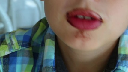 Closeup view of funny dirty mouth of kid after eating chocolate melted paste with spoon. Brown lips and teeth. Child licking spoon. Real time full hd video footage.
