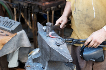 Blacksmith works a glowing metal on the anvil