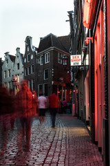 A street in the red light district of Amsterdam. On the street there is a sign  advertising a sex shop and an ATM © parkerspics