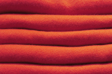 Stack of red woolen knitted sweaters close-up, texture, background