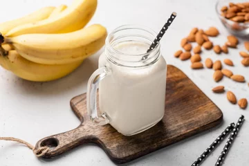 Photo sur Plexiglas Milk-shake Smoothie protéiné à la banane dans un verre à boire sur une planche de service en bois. Vue rapprochée