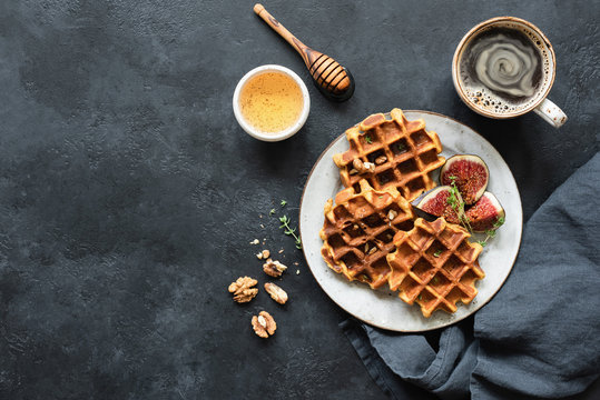 Whole wheat waffles with honey and figs on black concrete background. Top view, copy space for text