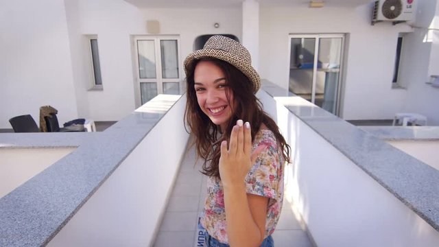 Beautiful woman in hat walking in hotel. Close up of smiling girl walk indore. Follow me concept. Cheerful girlfriend going in hotel back view. Pretty girl in hat walking at white corridor