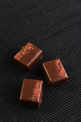 Luxury handmade bonbons decorated with pink salt on black background