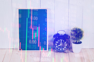 Double exposure of alarm clock with green chalkboard, financial graph, with candle stick and stock market screen, business planning vision and finance analysis