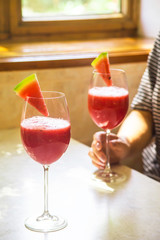 A woman takes a watermelon cocktail from the table in a glass. Fruit cocktails, detox and healthy eating concept