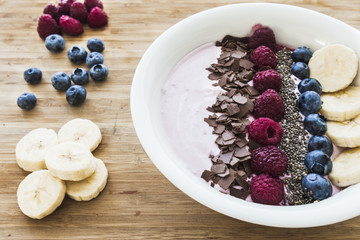 Smoothie bowl with fresh berries, banana, chia seeds and chocolate for healthy vegan and vegetarian diet breakfast