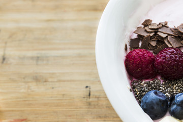 Smoothie bowl with fresh berries, banana, chia seeds and chocolate for healthy vegan and vegetarian diet breakfast