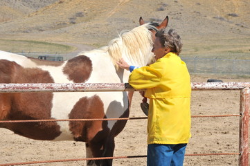 Mature female senior bonding with her horse on the ranch outdoors.