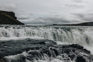 scenic view of beautiful mountain river flowing through highlands under cloudy sky in Iceland