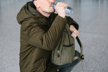 The traveler drinks water from the bottle. A person is going to make a rest.