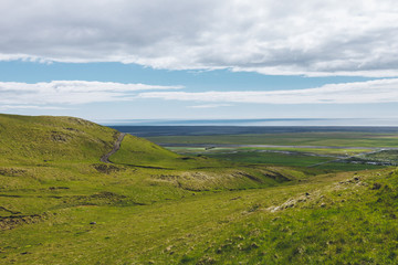 Fototapeta na wymiar scenic view of landscape with green highlands under cloudy blue sky in Iceland