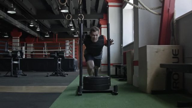 Sled push man pushing weights workout exercise at gym. Cross fit style