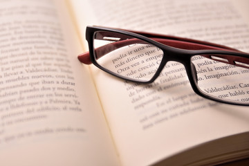 Black and red reading glasses on open book
