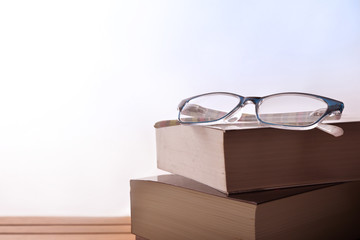 Woman reading glasses on stack of books