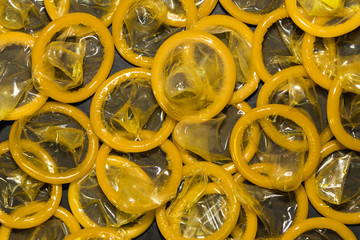 A bunch of yellow condoms on a black background