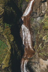 aerial view of river flowing down from mountain with sunlight in Fjadrargljufur Canyon in Iceland