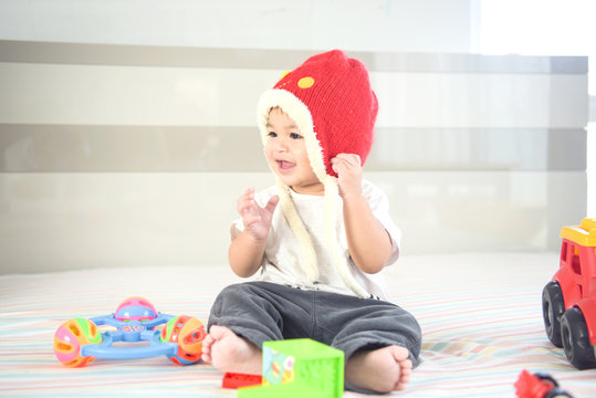 kid boy toddler playing with toy on bedroom at home.Happy laughing baby wearing bubble hat sitting on parents bed